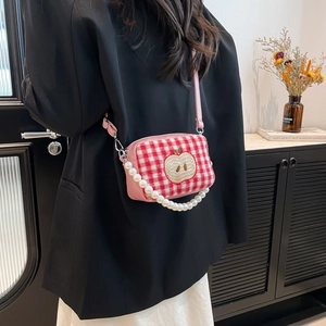 Pink plaid cosmetic bag with apple embroidery and pearl strap shown on shoulder
