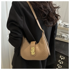 Detail of warm brown woven crescent bag featuring a prominent gold metal ring buckle