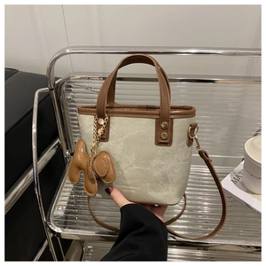 Détail du sac seau en toile et cuir avec un pendentif en forme de chien mignon accessoire
