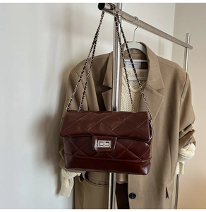 Détails de la texture matelassée brillante et du fermoir argenté du sac marron