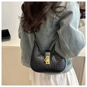 Detail of black crescent shoulder bag with straw texture and golden ring clasp