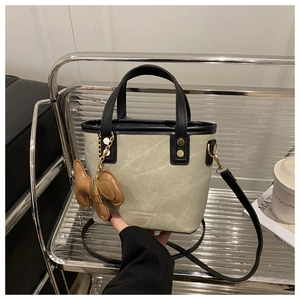 Détail du sac seau tendance avec bordure en cuir et breloque chien sur présentoir