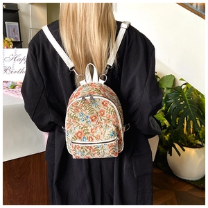 Detailed back view of a floral mini backpack with white leather straps on a model
