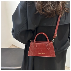 Detail of burgundy crocodile pattern mini bag with gold hardware and logo text