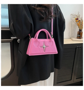 Pink trapezoid handbag with silver star buckle shown worn by a model in a modern office