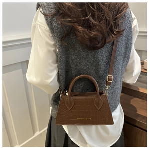 Detail view of dark brown crocodile embossed texture on a chic vintage leather handbag