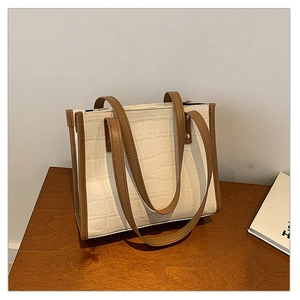 Detail shot of the crocodile texture on the white and brown contrast tote bag