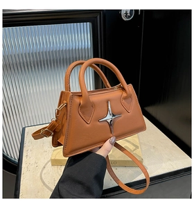 Close-up of a brown trapezoid handbag with a star-shaped metal buckle and round handle