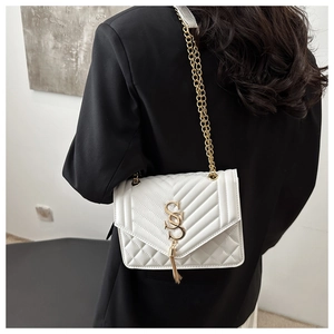 Close-up of white quilted leather texture with gold logo and tassel on a crossbody bag