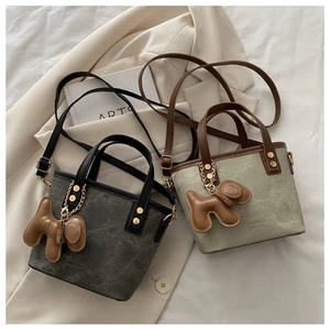 Détail de mini sacs cabas gris et verts avec poignées en cuir et pendentifs chien