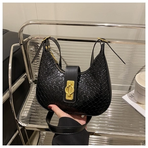 Close-up of black woven leather crescent bag featuring a prominent gold metal buckle