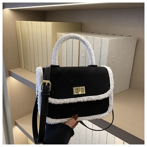 Detail of black quilted crossbody bag with white faux fur trim and gold metal turn-lock