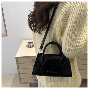 Detail of black crocodile embossed crossbody bag showing texture and golden logo on strap