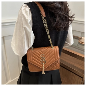 Detail of brown quilted leather bag with golden V-stitching and tassel chain strap