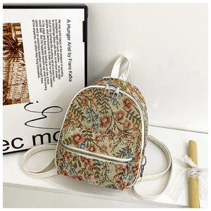 Detail of floral tapestry backpack with white leather trim and double zipper closure
