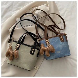 Détail du mini sac cabas avec texture toile, rivets dorés et charmant pendentif chien