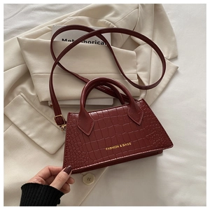 Detail of red crocodile texture on trapezoid bag with gold Fashion & Bags lettering