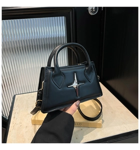 Close-up of black crossbody bag featuring a distinctive silver star metal hardware detail