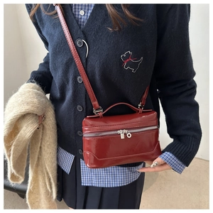 Detail of dark red patent leather square bag with silver zipper and glossy finish