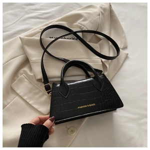 Detailed close-up of black crocodile pattern leather handbag with gold buckle and strap