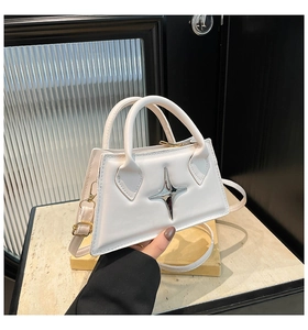 Close-up of white PU leather trapezoid handbag with silver star metallic detail and strap