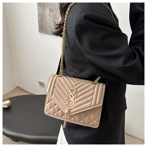 Détail du sac à bandoulière en cuir matelassé beige avec chaîne dorée et gland