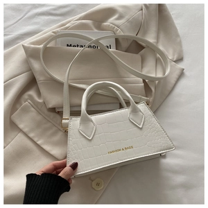 Close-up of white crocodile pattern tote bag styled on minimalist cream office blazer
