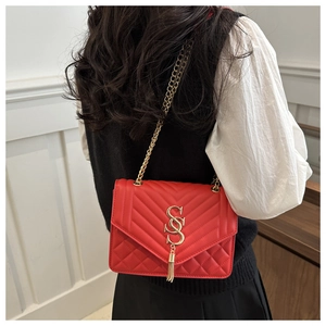 Détail du sac à bandoulière en cuir rouge matelassé avec pompon doré et chaîne