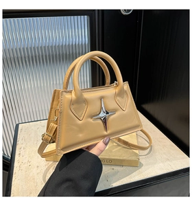 Detail of khaki square bag with silver star hardware and handle on marble surface