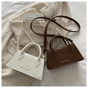 Detail showing white and brown crocodile embossed mini crossbody bags with gold hardware