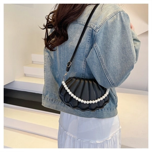 Detail of shell-shaped crossbody bag with pearl strap and golden metal hardware