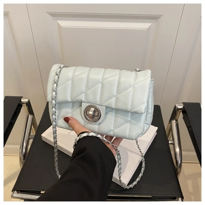 Détail d'un sac à bandoulière matelassé bleu clair avec chaîne et fermoir rotatif