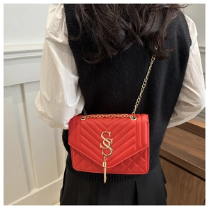 Détail du sac bandoulière en cuir rouge matelassé avec logo SS doré et pompon élégant