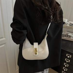 White woven hobo shoulder bag with golden round buckle shown on a model in a black suit