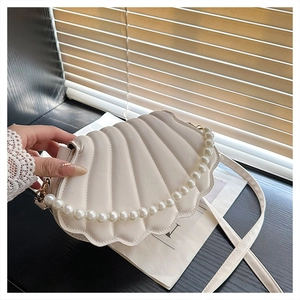 Detail of white shell-shaped handbag with textured PU leather and pearl handle