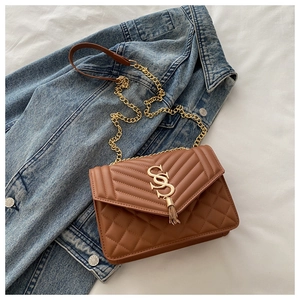 Détail du sac matelassé marron avec logo SS doré et pendentif à pompon élégant