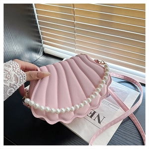 Pink shell crossbody bag featuring elegant faux pearl handle and quilted texture detail