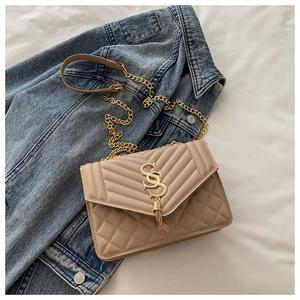 Détail du sac matelassé beige avec logo SS doré et élégant pendentif à franges