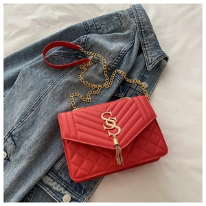 Détail du sac bandoulière en cuir matelassé rouge avec logo SS doré et chaîne sur denim