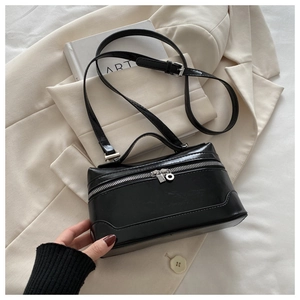 Detail of minimalist black leather crossbody square bag on stylish cream blazer jacket