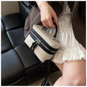 Detail view of two-tone canvas and black leather box handbag with silver zipper hardware