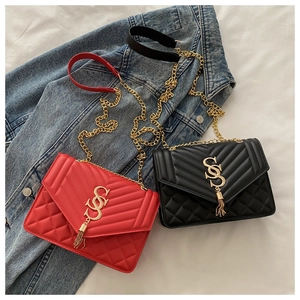 Détail de sacs en cuir matelassé rouge et noir avec chaînes dorées et pendentifs glands