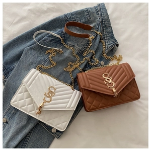 Détail de sacs à chaîne matelassés avec logo doré et pompon élégant sur denim