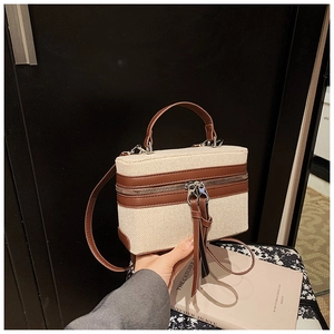 Detail of canvas box bag featuring brown leather trim and stylish long leather tassels