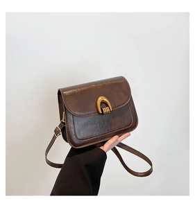 Detail of vintage brown PU leather crossbody bag with golden arched metal clasp
