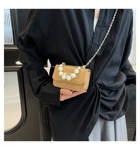Detail of khaki faux crocodile skin bag featuring elegant pearl handle and gold chain