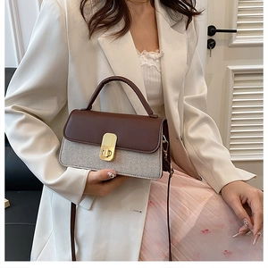 Detail of vintage textured crossbody bag showing gold lock and brown leather flap