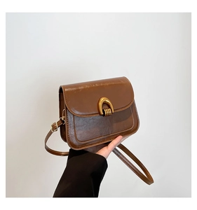 Detailed close-up of brown vintage saddle bag with gold U-shaped metal buckle hardware