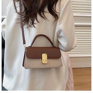 Detail of vintage square bag with golden twist lock and brown leather canvas stitching