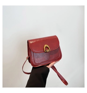 Detail of vintage red leather saddle bag with U-shaped gold hardware buckle and slim strap